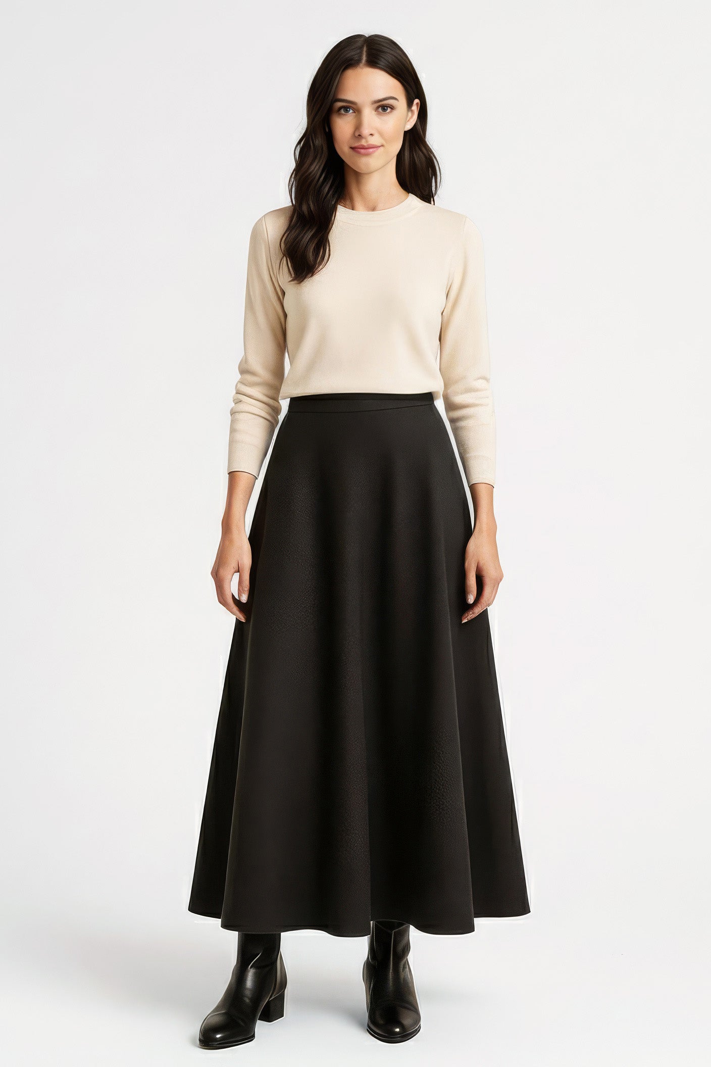 woman wearing long black winter skirt with beige sweater on white background.