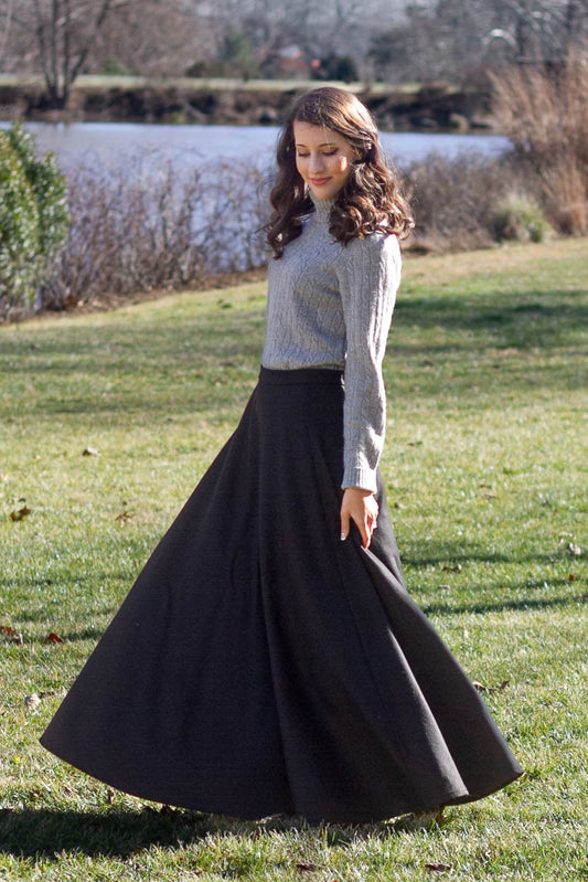 woman twirling in field in black long wool skirt