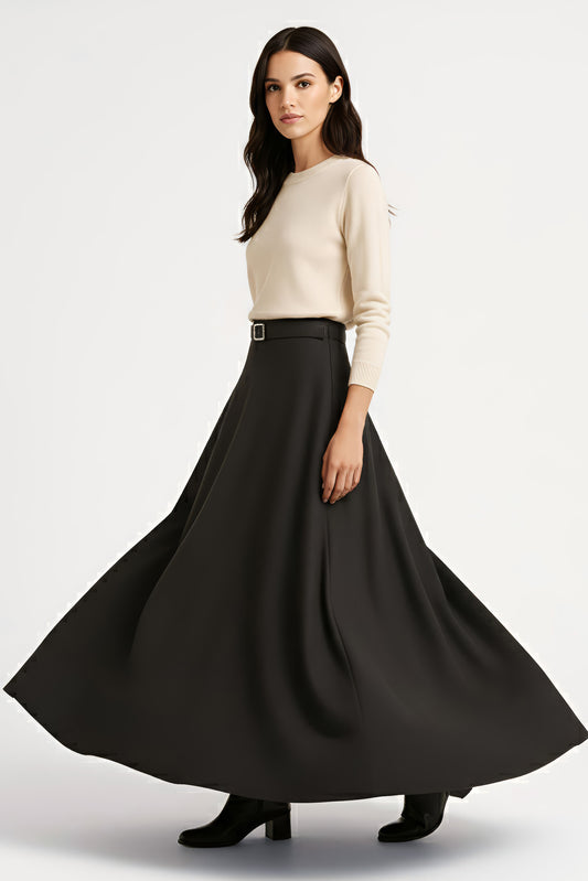 woman twirling in beige sweater and full black wool maxi skirt on white background