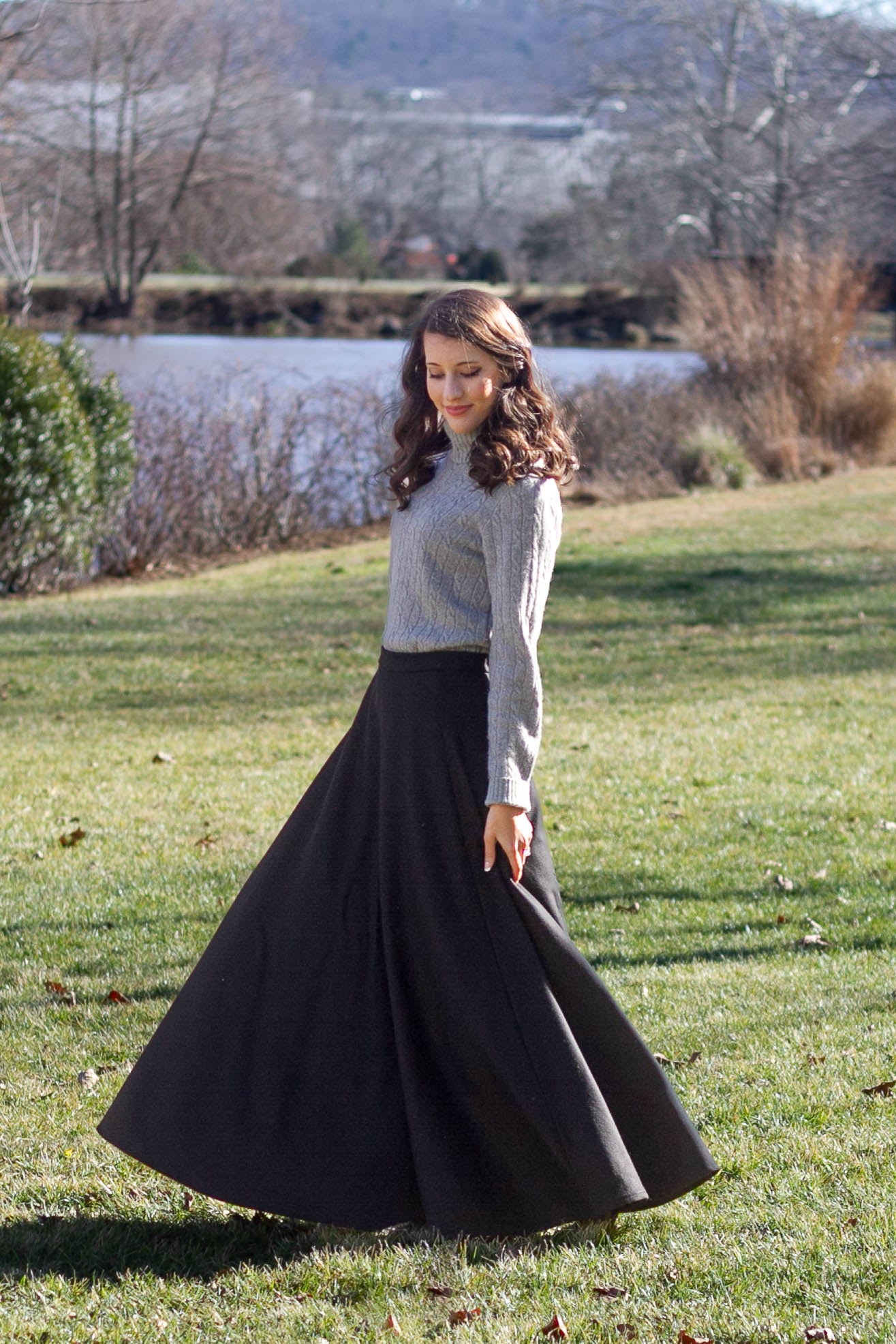 woman twirling in field in black long wool skirt