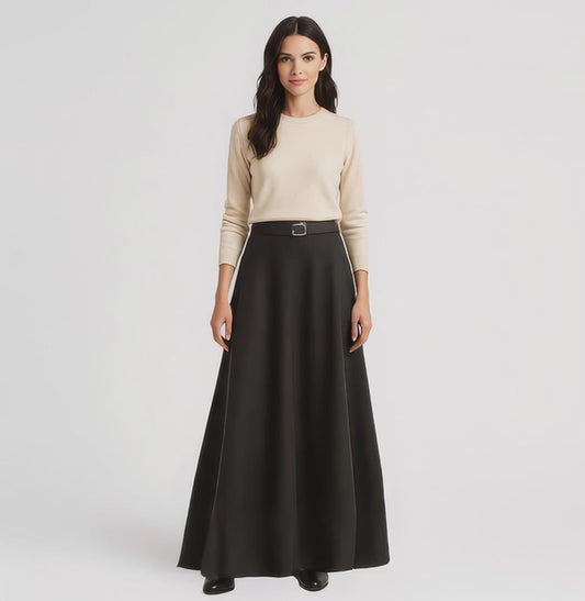video of model wearing beige sweater, belt and black maxi skirt on white background.