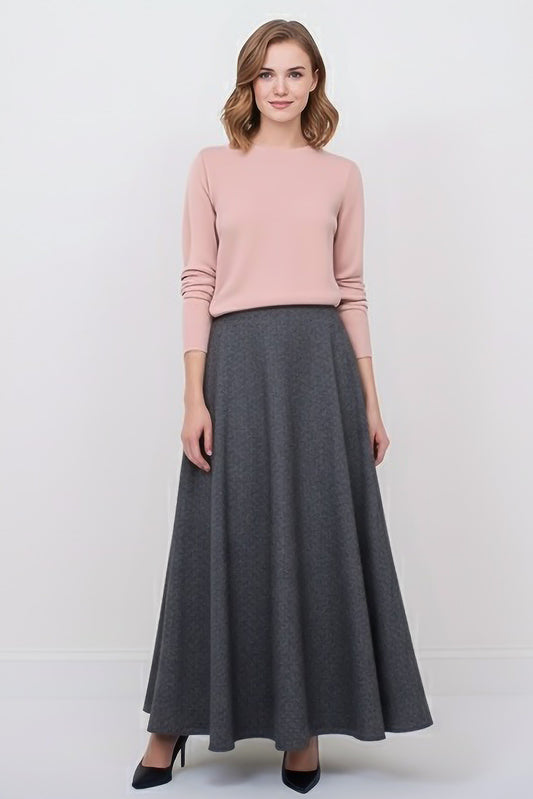 Woman wearing a pink sweater and dark gray wool maxi skirt.
